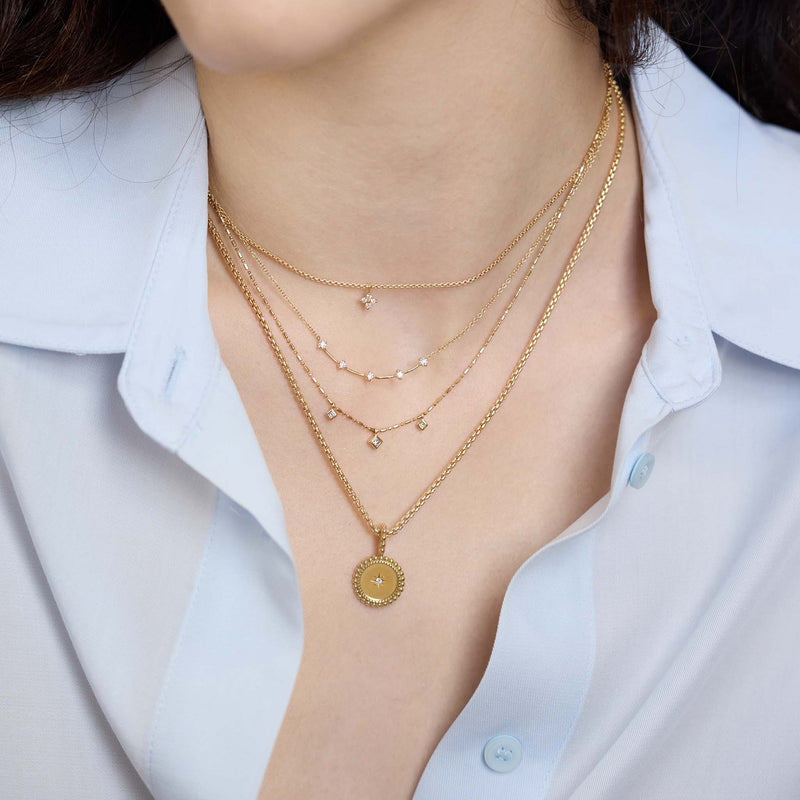 Zoe Chicco 14K Gold and diamond layered necklaces on a person wearing a blue shirt