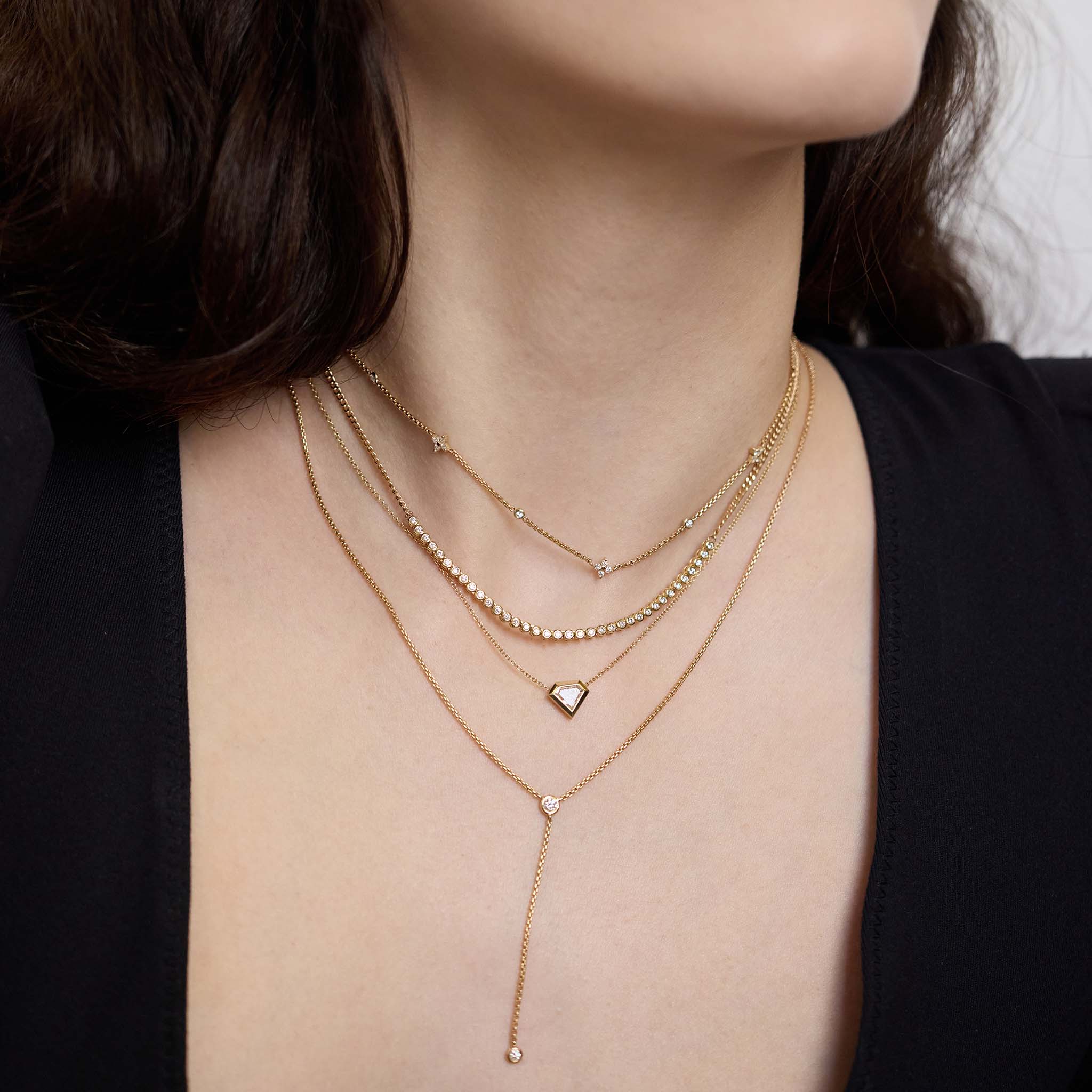Zoe Chicco 14K gold necklaces including a one of a kind Shield Diamond Bezel Necklace layered on a womans neck