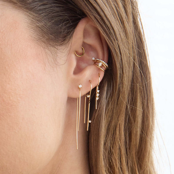 Zoe Chicco 14K  Close-up of an ear with gold earrings on a neutral background