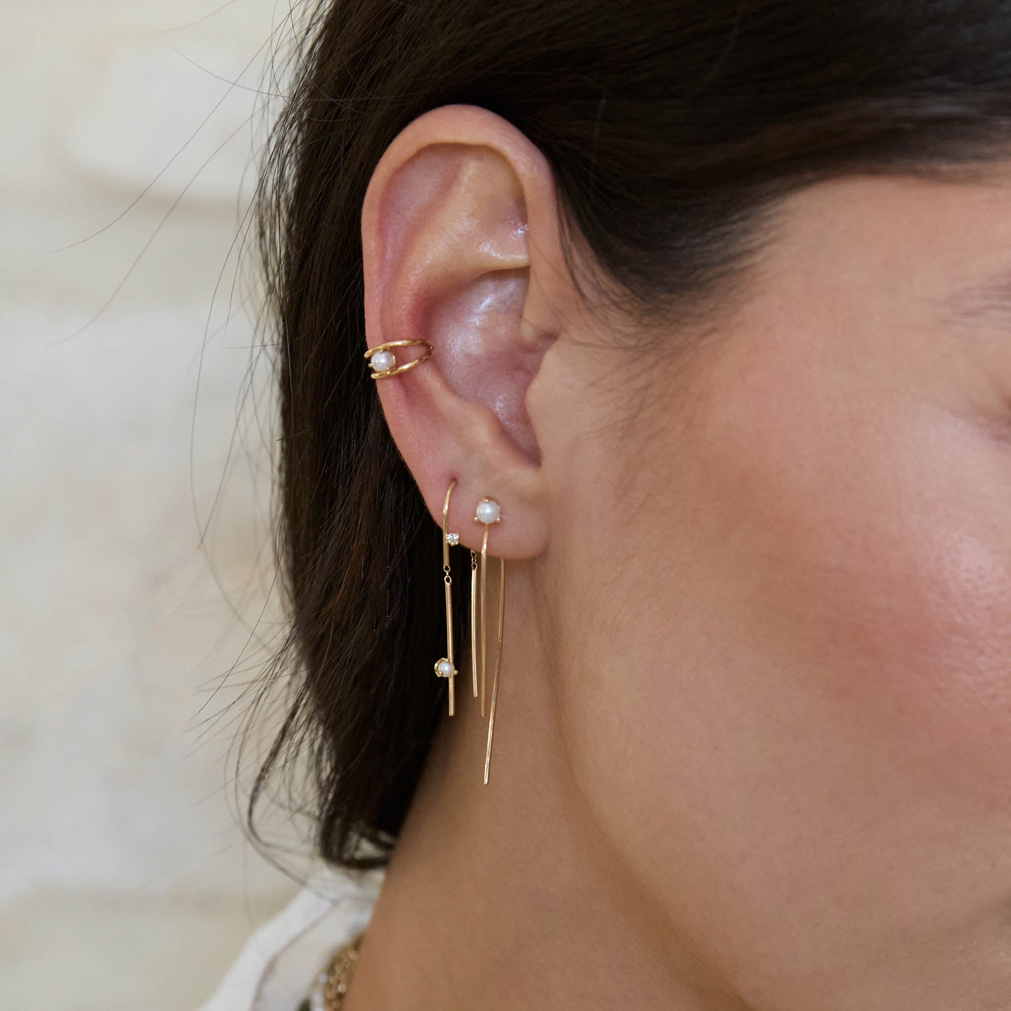 Close up of an ear wearing Zoe Chicco 14k gold wire threader earrings with pearls and an ear cuff