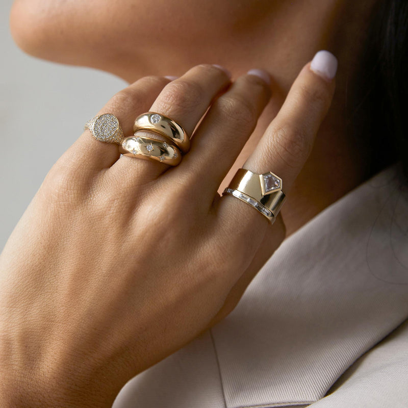 a woman wearing a One of a Kind Zoë Chicco 14k Gold .67 ctw Shield Diamond Bezel Wide Cigar Band Ring stacked with a Baguette Diamond Eternity Ring on her index finger