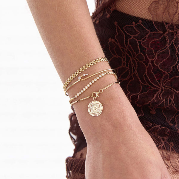 Zoe Chicco 14K wrist wearing multiple gold and diamond bracelets and cuffs