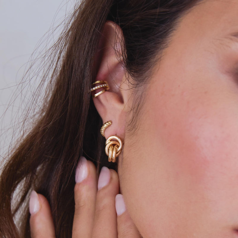 close up of a woman's ear wearing a Zoë Chicco 14k Gold Double Linked Knot Drop Earring layered with a 14k Gold Twisted Thick Huggie Hoop in her second piercing