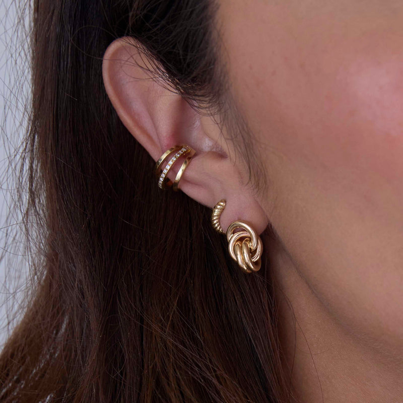 close up of a woman's ear wearing a Zoë Chicco 14k Gold Double Linked Knot Drop Earring layered with a 14k Gold Twisted Thick Huggie Hoop in her second piercing