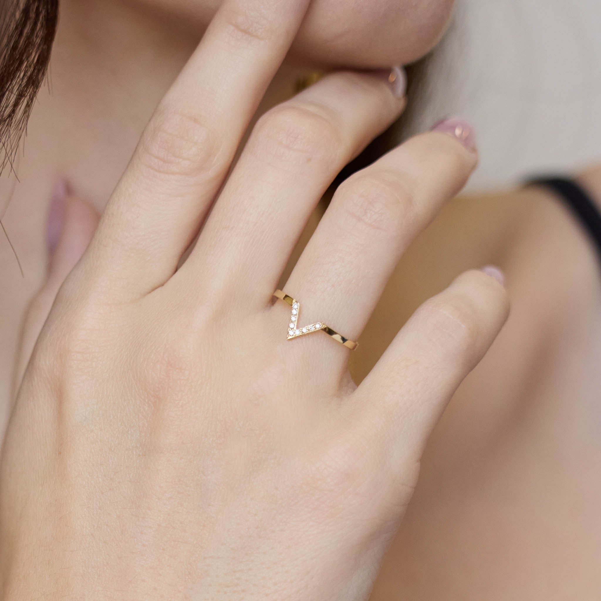 Zoe Chicco 14k gold ring with a V-shaped design on a person's finger on a blurred background
