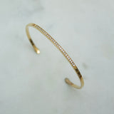 Gold cuff bracelet with pave diamonds on a light gray background
