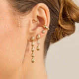 Close up of an ear wearing Zoe Chicco 14k gold teardrop shaped dangle earrings on a neutral background