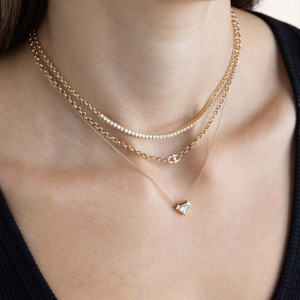 a woman in a black top wearing a Zoë Chicco 14k Gold 3 Prong Diamond Open Link Medium Rolo Chain Necklace layered with a Prong Diamond Tennis Segment Rolo Chain Necklace and a one of a kind Shield Diamond Bezel Necklace