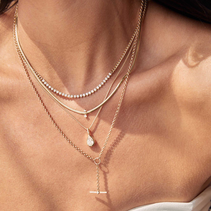 woman's neck wearing a Zoë Chicco 14k Gold Princess Diamond & Diamond Bar Toggle Lariat Necklace layered with a one of a kind diamond pendant necklace, snake chain necklace, and diamond tennis segment necklace