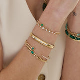 woman's wrist wearing a Zoë Chicco 14k Gold Prong Emerald Quad Box Chain Bracelet stacked with a 14k Large Linked Mixed Cut Diamond Bolo Bracelet, 14k Graduated Diamonds Wide Half Round Cuff, 14k Emerald Cut Emerald & Pavé Diamond Cuff, and a 14k Medium Curb Chain Emerald Cut Emerald Bezel Bracelet
