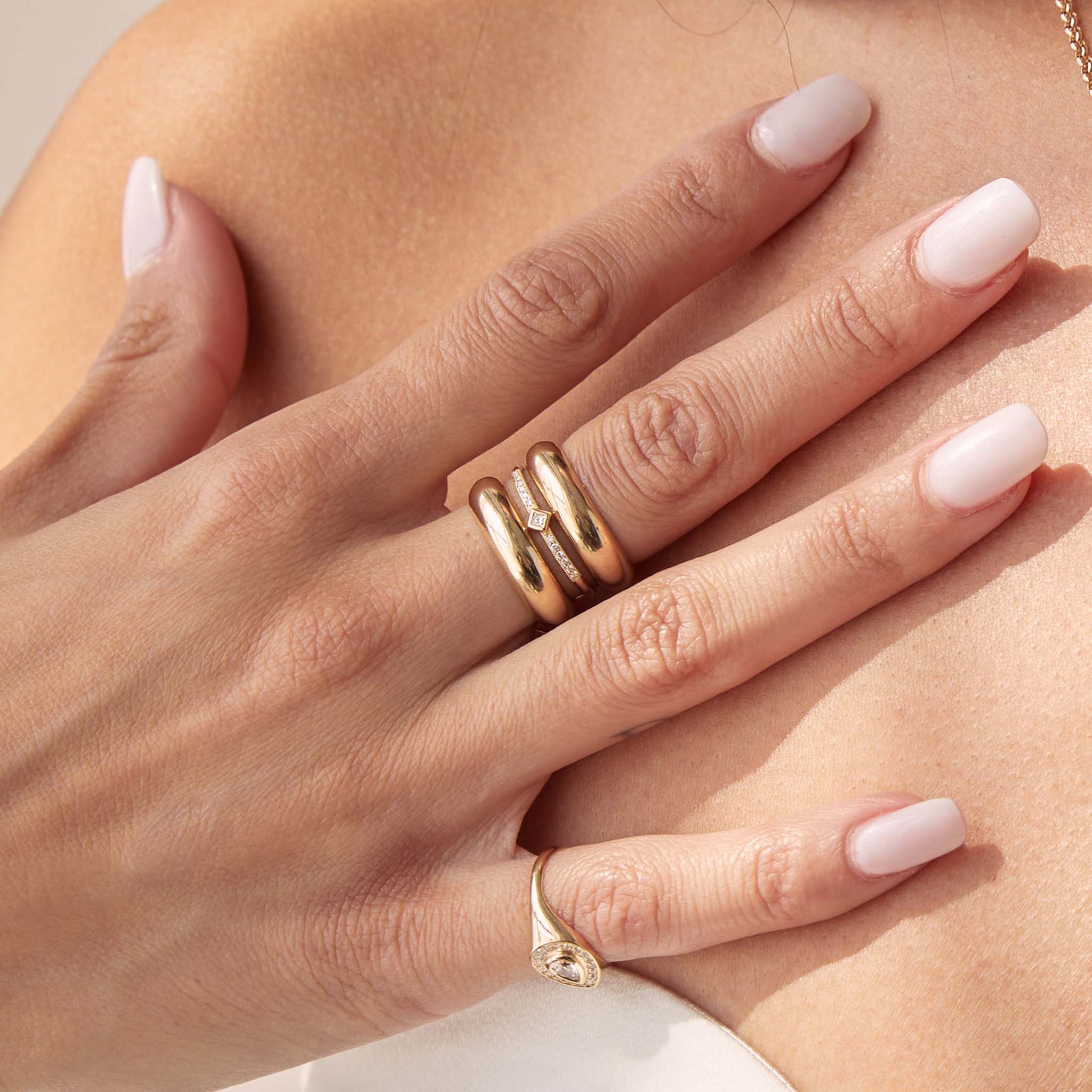 close up of woman's hand wearing a Zoë Chicco 14k Gold Princess Diamond with Demi Pavé Band Ring stacked between two gold half round rings