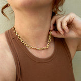 A woman in a brown top is wearing Zoe Chicco's 14k Gold XXL Square Oval Link Chain Necklace.