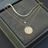 Inside a gray jewelry box are three layering necklaces including the small snake chain, floating diamond on tube chain and the small sunbeam medallion necklace.