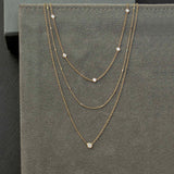 On a gray background 2 layering necklaces shown:  a double strand necklace with floating diamond and a 5 floating diamond short necklace.  Both are  in 14k yellow gold.