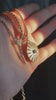 Video of hand holding two Zoe Chicco 14k gold chain necklaces with diamonds and pendants in the sunshine.