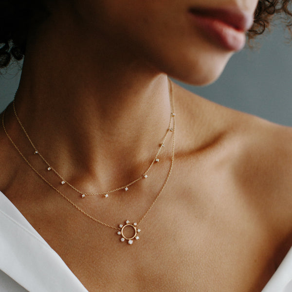 woman wearing Zoë Chicco 14kt Gold Prong Diamond Sunburst Circle Necklace layered with a diamond station necklace