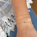 woman's wrist wearing Zoë Chicco 14kt Gold Bezel Turquoise Bracelet stacked with a round disc bracelet and pave diamond disc bracelet