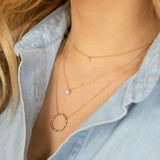 woman in blue shirt wearing Zoë Chicco 14kt Gold Diamond Bezel & Pearl Layered Chain Necklace layered with a circle pendant necklace