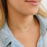 close up of woman in denim shirt wearing a Zoë Chicco 14k Gold Midi Bitty Pavé Diamond Star of David Necklace layered with a Diamond Bezel Pendant Necklace