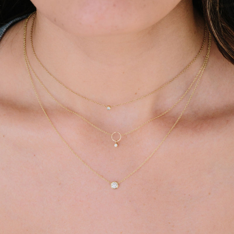 woman wearing Zoë Chicco 14kt Gold Circle Necklace with Dangling Diamond Bezel layered with a floating diamond and diamond bezel necklace
