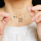 woman holding up a chain with Zoë Chicco 14kt Gold Blue Sapphire Charm Pendant and three other charms on it