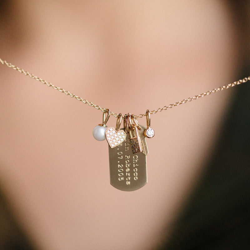 close up of necklace with Zoë Chicco 14kt Gold Vertical Text Small Dog Tag Charm and other charms