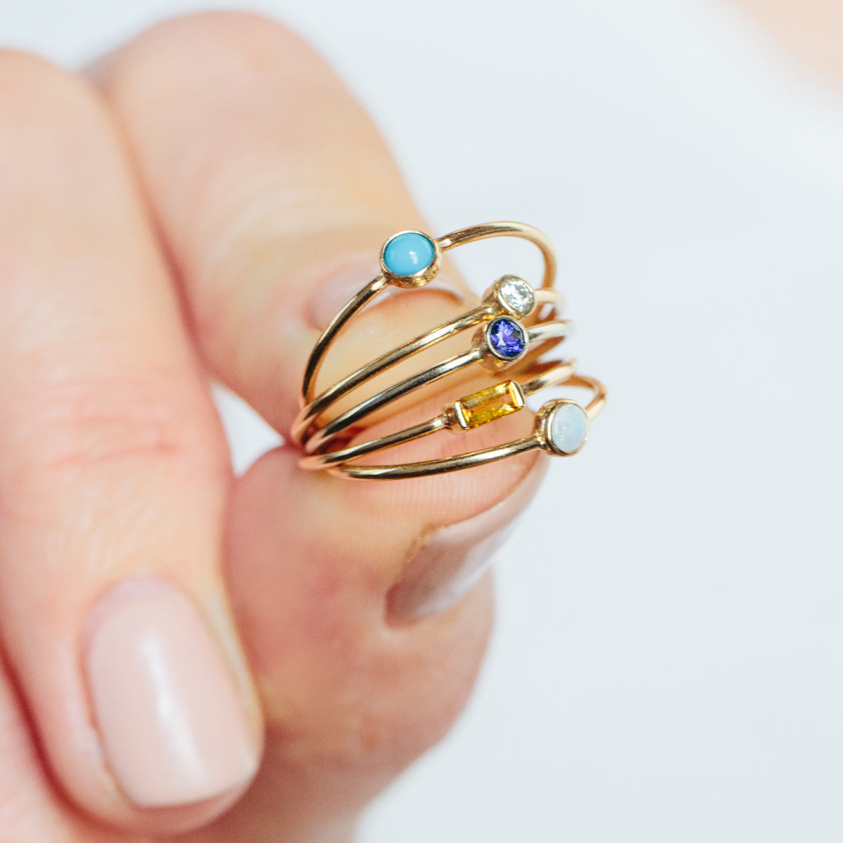 girl holding a few zoe chicoc birthstone rings with her two fingers