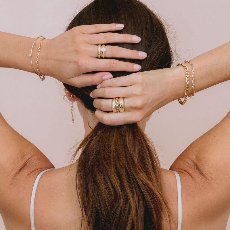 back of woman's head with hands resting on her hair and wearing Zoë Chicco 14k Gold Prong Diamond Cuff & Medium Square Oval Chain Double Bracelet on her wrist