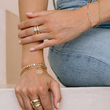 close up of woman's hand resting on a ledge wearing Zoë Chicco 14k Gold Diamond Evil Eye Medallion Square Oval Link Bracelet on her wrist