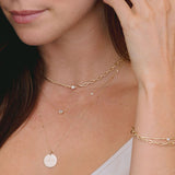 close up of woman's neck wearing Zoë Chicco 14k Gold Small "exhale" Disc Pendant on Bar & Cable Chain Necklace layered with two other necklaces