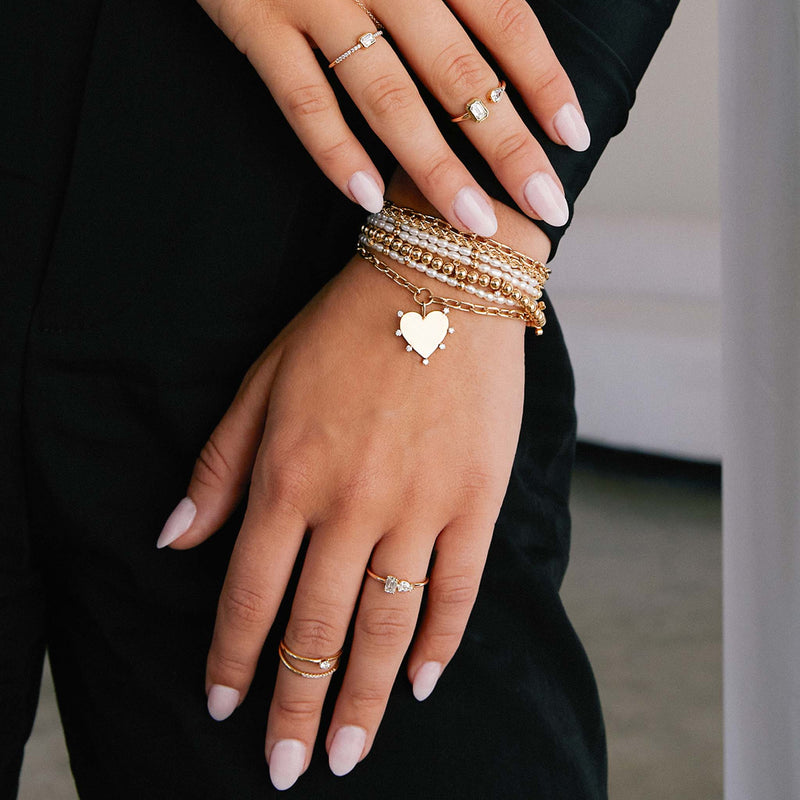 woman's wrist wearing a Zoë Chicco 14k Gold Bead & Rice Pearl Triple Wrap Convertible Bracelet  resting on her leg