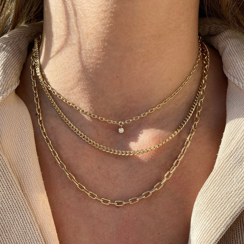 woman in beige shirt wearing a 14k Small Curb Chain & Medium Square Oval Link Layered Necklace