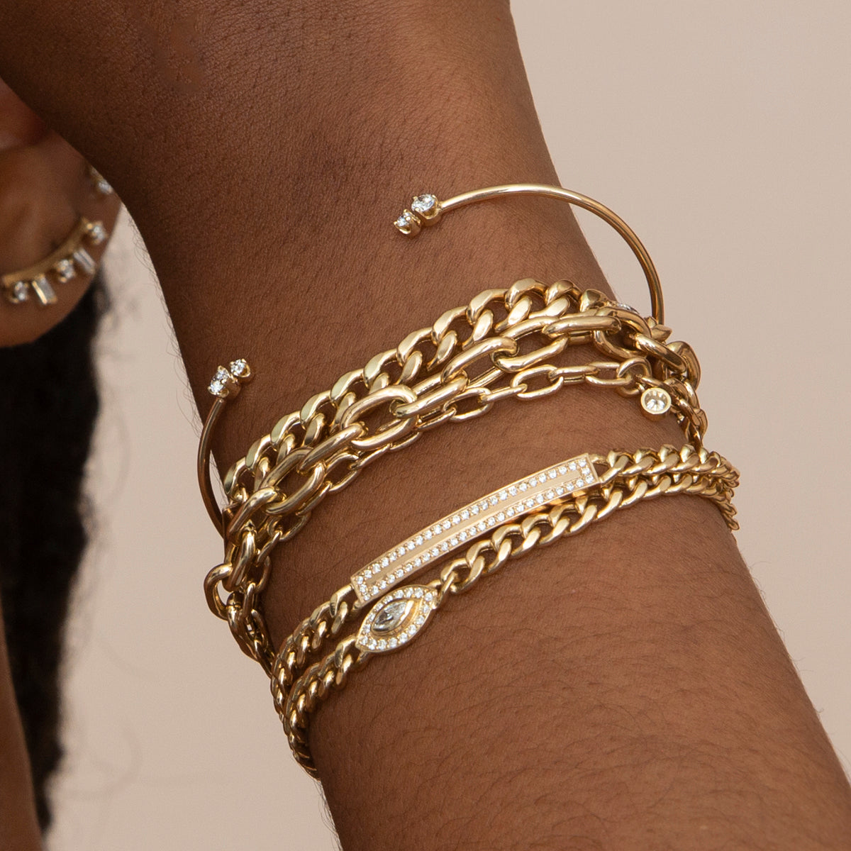 woman's wrist wearing Zoe Chicco 14kt Marquise Cut Diamond Halo Medium Curb Chain Bracelet with a Mixed Diamond Thin Wire Cuff, several heavy chain bracelets, and a Medium Curb Chain ID with Diamond Border bracelet
