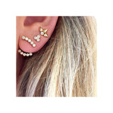 woman's ear wearing Zoë Chicco 14kt Gold 5 Diamond Bezel Curved Bar Stud Earring with a ear charm