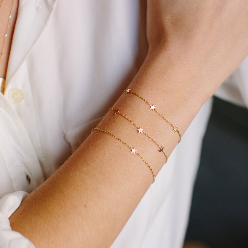 woman's wrist wearing a Zoë Chicco 14k Gold Itty Bitty Star Trio Station Bracelet