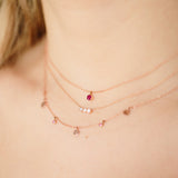 close up of woman wearing Zoe Chicco 14kt Gold 3 Diamond Bezel Horizontal Bar Necklace with a Ruby Pendant Necklace