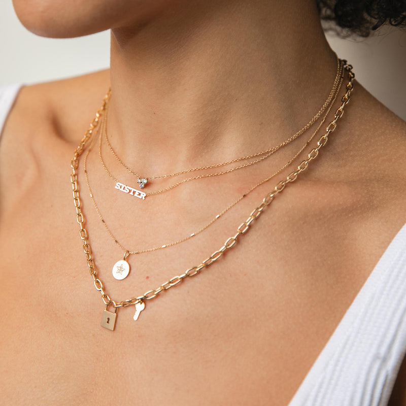 woman wearing Zoe Chicco 14k Gold Large 3 Mixed Prong Diamond Necklace, Itty Bitty Sister Necklace, Pave Diamond Star Disc Necklace, and a Padlock Pendant and Key Charm Square Oval Chain Link Necklace
