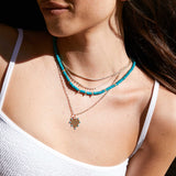 Woman in white tank top wearing a Zoë Chicco 14k Gold 15 Linked Graduating Prong Diamond Necklace and Prong Diamond Tennis Necklace layered with a 14k Gold & Turquoise Rondelle Bead Necklace with 3 Prong Diamonds and 7 Turquoise Heart Square Oval Chain Necklace.