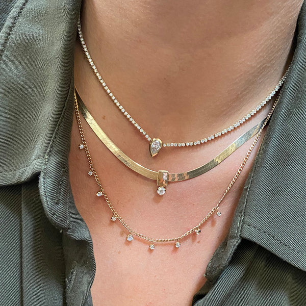 woman in green shirt wearing Zoë Chicco 14k Gold Prong Diamond Tennis Necklace with Pear Diamond Pendant layered with a Herringbone Chain Diamond Necklace