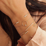 woman's wrist wearing Zoë Chicco 14kt Gold 3 Diamond Bezel Bar Open Cuff Bracelet layered with other diamond bracelets