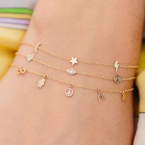 woman's wrist wearing Zoë Chicco 14kt Gold Peace and Luck Itty Bitty Station Bracelet stacked with two Itty Bitty station bracelets