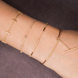 woman's wrist wearing Zoë Chicco 14kt Gold Graduated Diamond Baguette Bolo Bracelet with three other gold bar bracelets