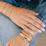 woman in denim resting her hands on her lap wearing a Zoë Chicco 14k Gold Small Curb Chain Ring with Emerald Cut Diamond on her ring finger