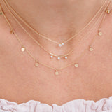 close up of woman's neck wearing Zoë Chicco 14kt Gold 9 Itty Bitty Round Disc Charm Necklace