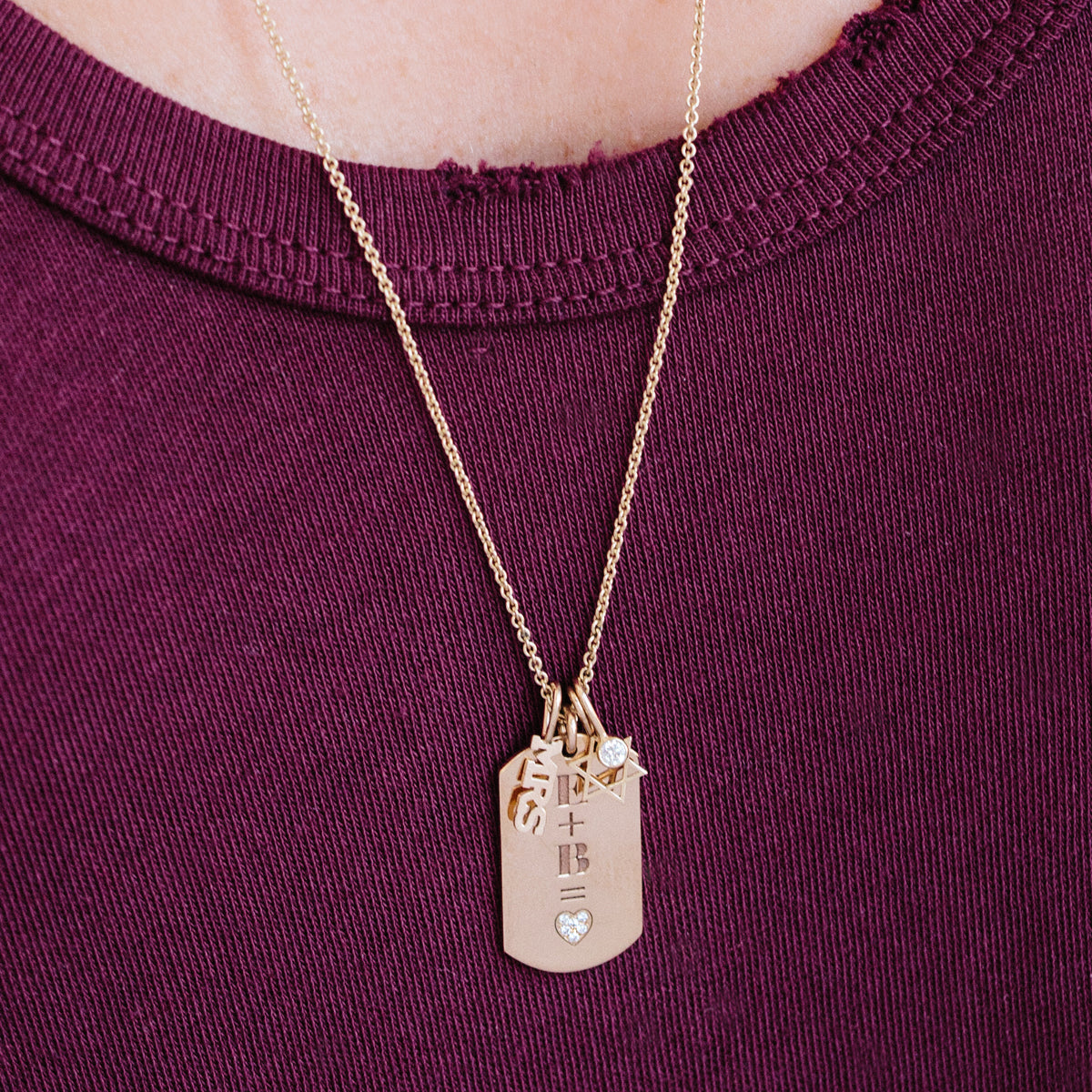 woman in purple shirt wearing a Zoë Chicco 14kt Yellow Gold Thicker Cable Chain Necklace with various charm pendants dangling