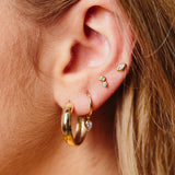 woman's ear wearing Zoë Chicco 14kt Gold Medium Wide Round Hoop Earring with three diamond earrings