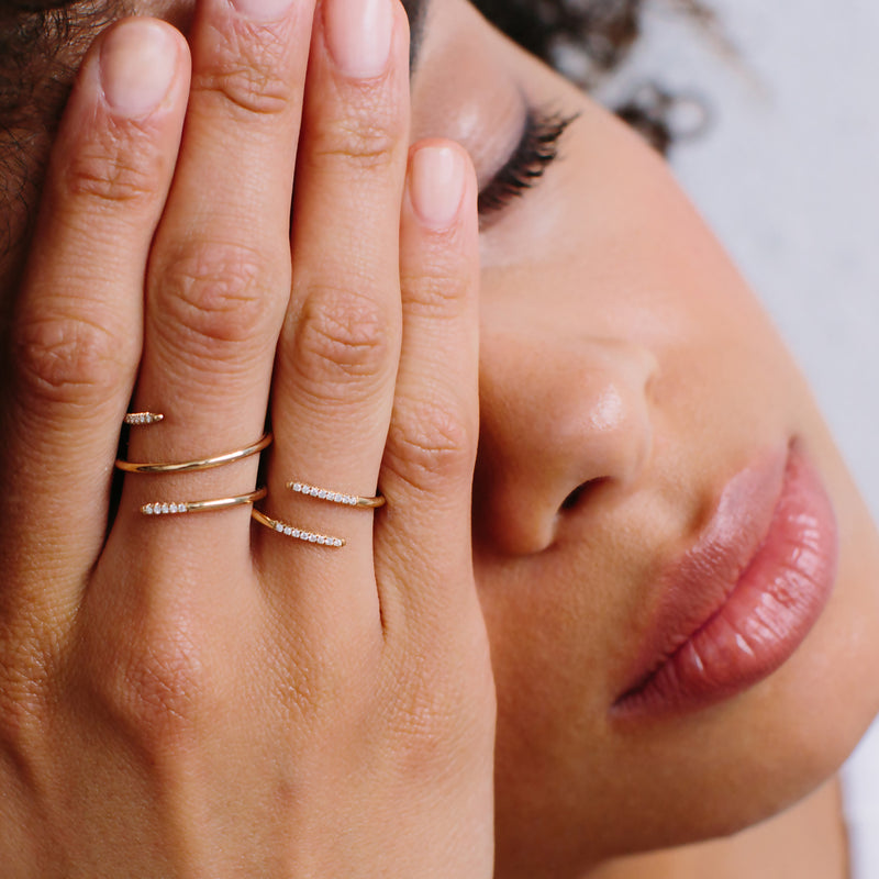 woman wearing two wrap around yellow gold rings with pave diamonds