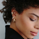 woman in black top wearing Zoë Chicco 14kt Gold Pave Diamond Chubby Huggie Hoop Earring with two ear cuffs