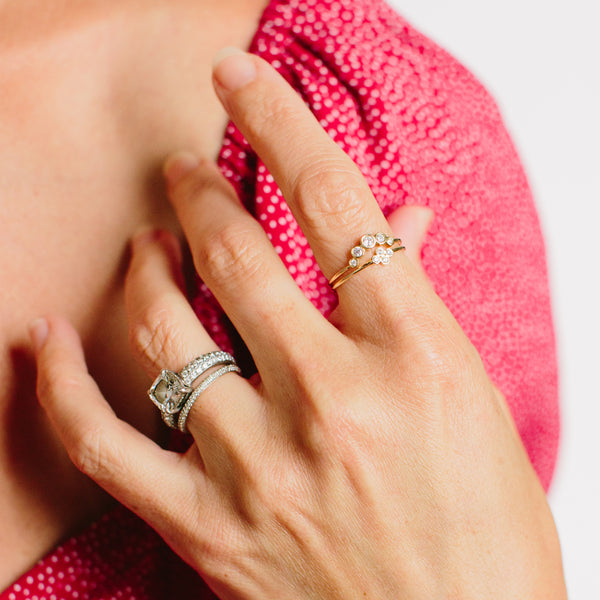 woman in pink top wearing Zoë Chicco 14kt Gold Tiny Quad White Diamond Bezel Ring on index finger