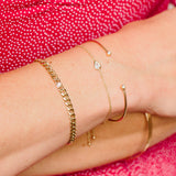 woman's wrist wearing Zoe Chicco diamond bezel cuff, pear diamond bezel bracelet, and medium curb chain bracelet with floating diamond